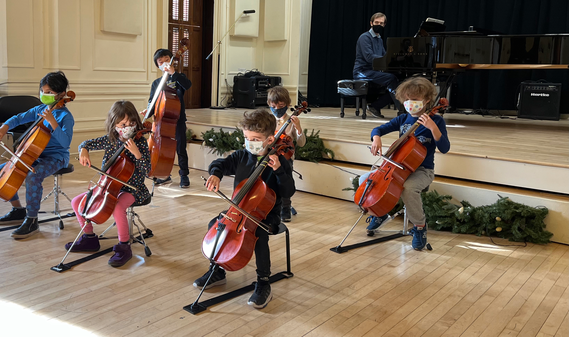 Young cellists performing together in a studio recital with piano accompaniment