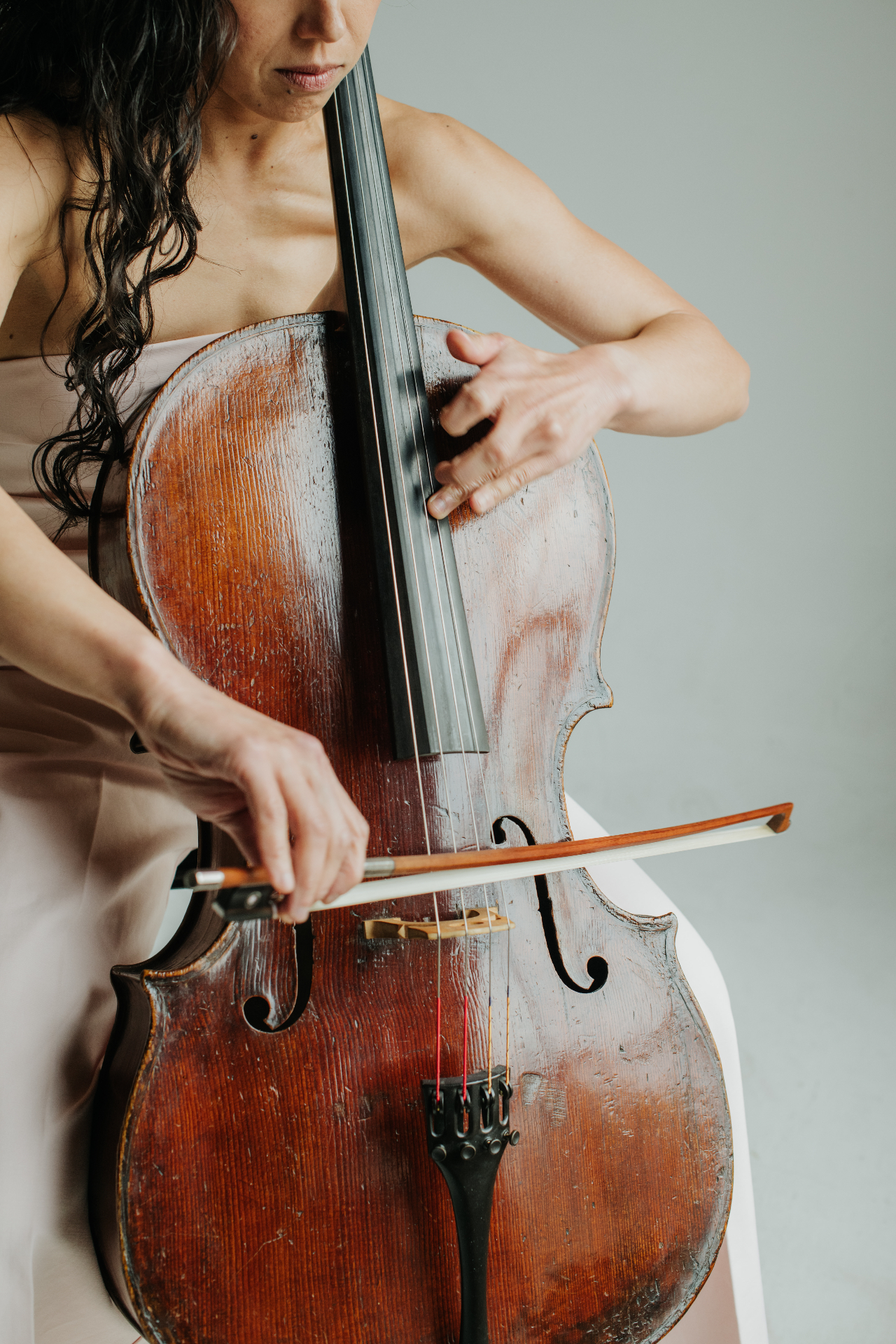 Cellist mid-bow stroke in a warm, natural-light studio