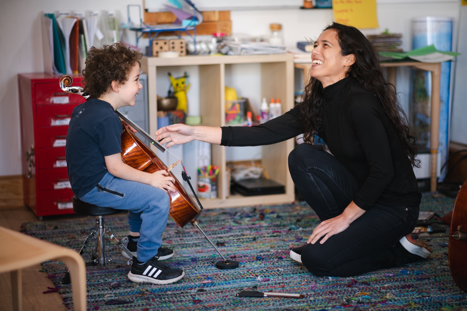 Paloma laughing with a young cello student mid-lesson